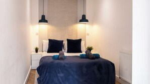 Ein Schlafzimmer mit einem Bett, zwei Nachttischen, einem Heizkörper und zwei Pendelleuchten.