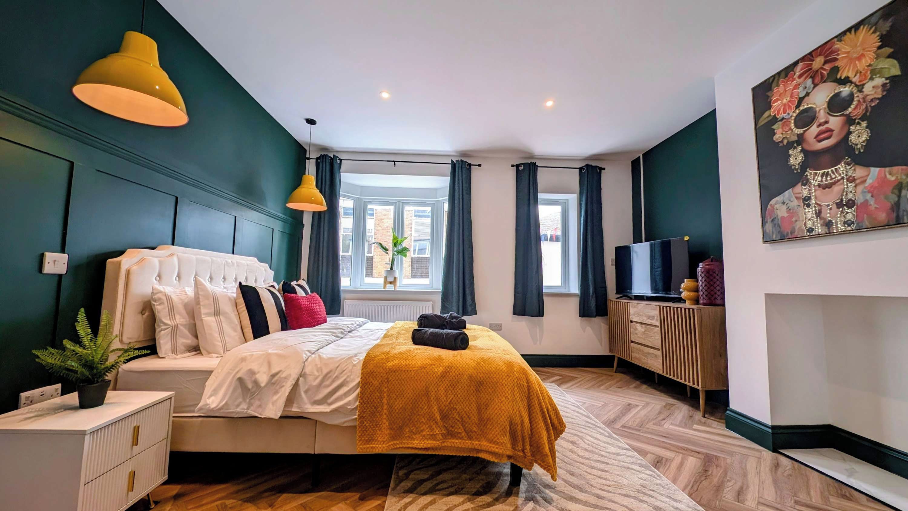 A modern bedroom with a bed, bedside tables, a TV, and a window with curtains.