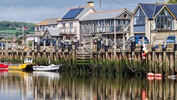 Propiedad frente al agua con un muelle, barcos y casas con ventanas grandes y paneles solares.