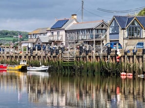 Propiedad frente al agua con un muelle, barcos y casas con ventanas grandes y paneles solares.