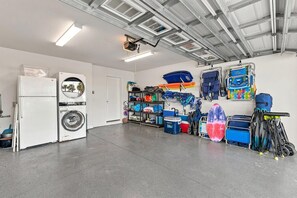 A laundry room with appliances, a wall-mounted washing machine, and a ceiling-mounted projector. - Rooftop at 202 (New Smyrna Beach)