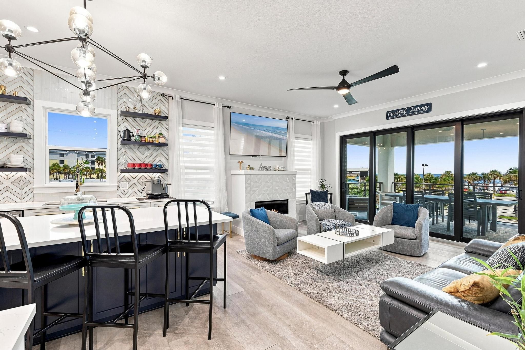 A modern living room with a dining area, a fireplace, and a view of the ocean.