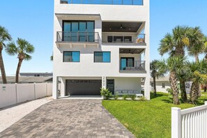 A modern multi-story building with a garage, a balcony, and a well-maintained lawn. - Rooftop at 202 (New Smyrna Beach)