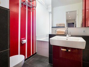 A bathroom with a toilet, a sink, and a mirror. - Holiday Apartment With 2 Bedrooms (Norderney)