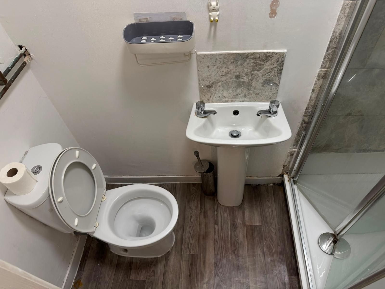 Un baño con inodoro, lavamanos y zona de ducha.