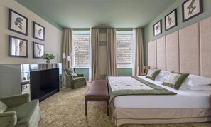 A hotel room with a bed, a TV, a seating area, and a window with curtains. - STUNNING 5-BEDROOM HOME WITH PRIVATE TERRACE & PIAZZA VIEWS (Firenze)