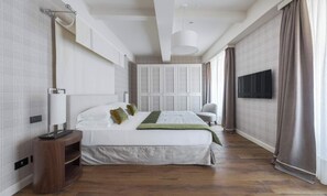 Ein modernes Hotelzimmer mit einem großen Bett, einem Nachttisch mit Lampe, einem flachbildfernseher an der Wand und einem großen Fenster mit Vorhängen.