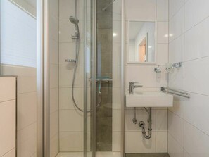 Une salle de bain moderne avec une douche à parois de verre, un lavabo blanc et un miroir.