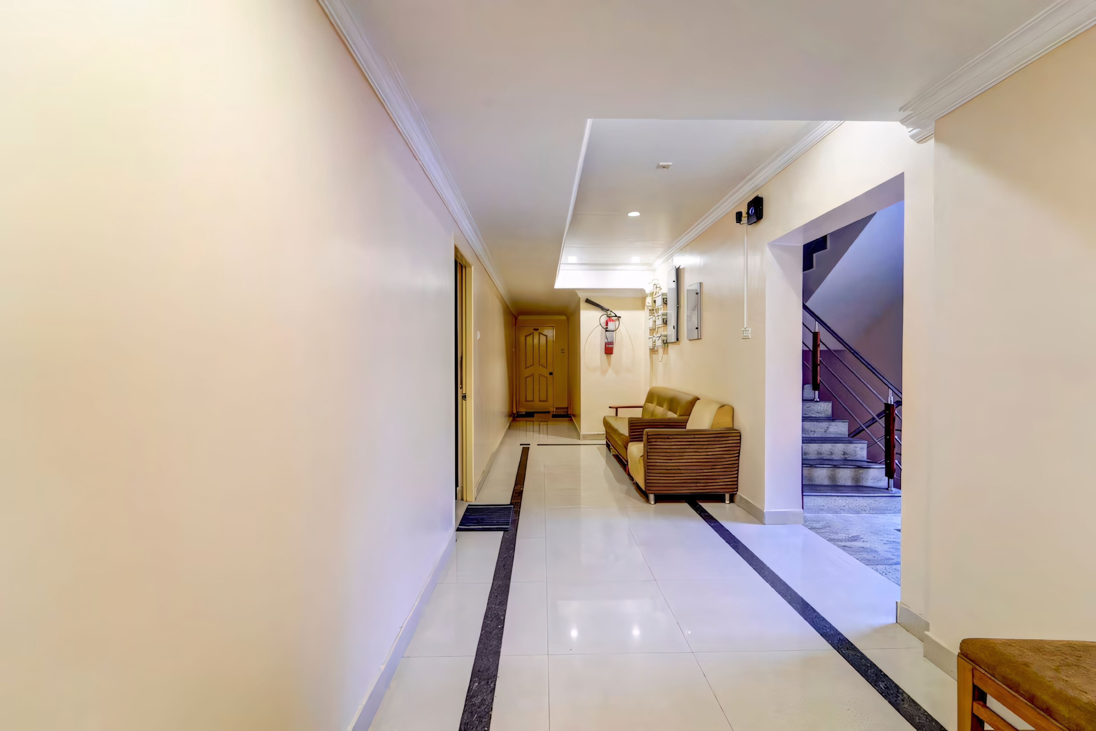 Un pasillo con un sofá, una escalera y una puerta que da a otra habitación.
