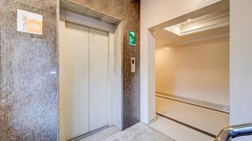 Un ascensor con un cartel que indica uso exclusivo para empleados, un letrero de salida de incendios, y un interior limpio y moderno con suelo de mármol.
