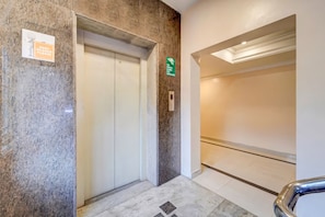 An elevator with a sign indicating it is for staff use only, a fire exit sign, and a clean, modern interior with a marble floor. - XOTEL ASHOKNAGAR (Chennai)