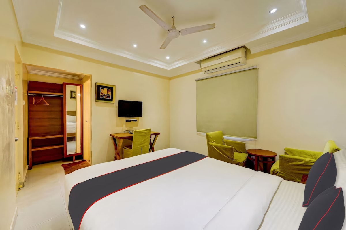 A hotel room with a bed, a desk, a chair, a television, and a ceiling fan.