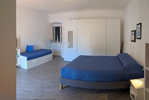 Un dormitorio con dos camas, un armario y un espejo.
