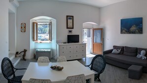 Una sala moderna con comedor, sofá, televisor y una cocina con refrigerador.