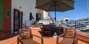 An outdoor terrace with wooden furniture, a table, and an umbrella.