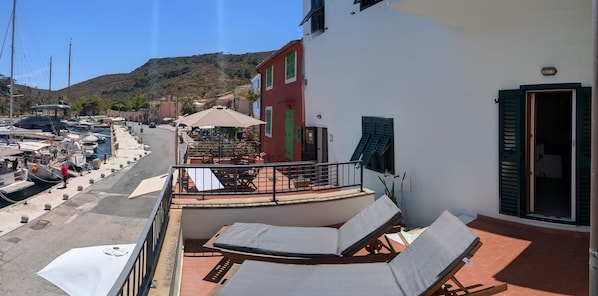 A balcony with a table and chairs, overlooking a marina with boats.