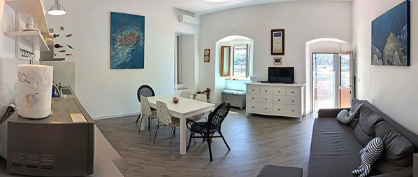 A modern living space with a dining area, kitchen, and seating area.