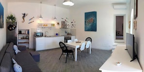 Un espace de vie compact comprenant un coin cuisine, un coin repas et un coin salon.