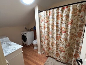 Ein Badezimmer mit Waschmaschine, Toilette und Duschvorhang.