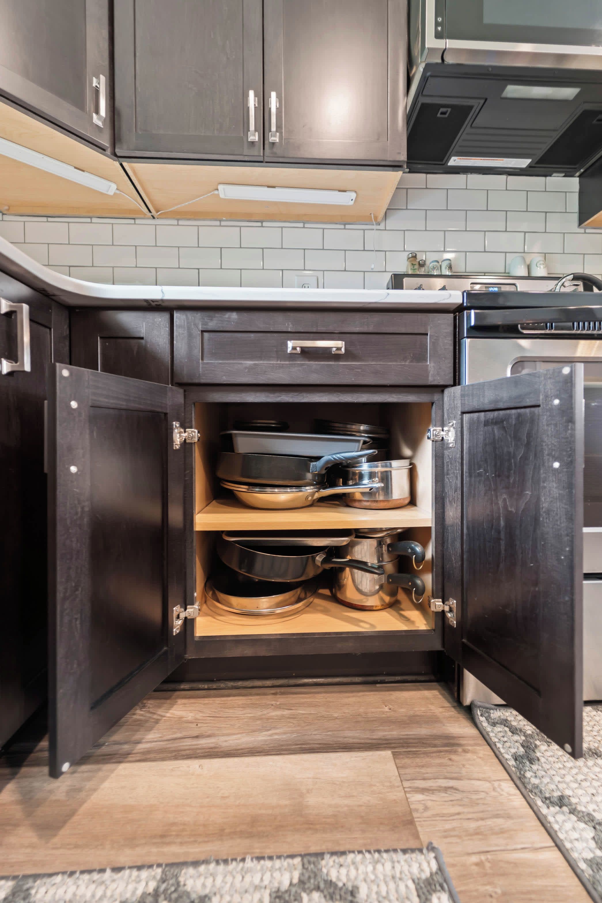 A kitchen with dark wooden cabinets, a built-in oven, and a countertop with a kettle and other appliances.