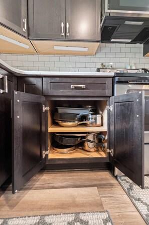 Une cuisine avec des meubles de rangement en bois foncé, un four encastré et un plan de travail sur lequel se trouvent une bouilloire et d’autres appareils.