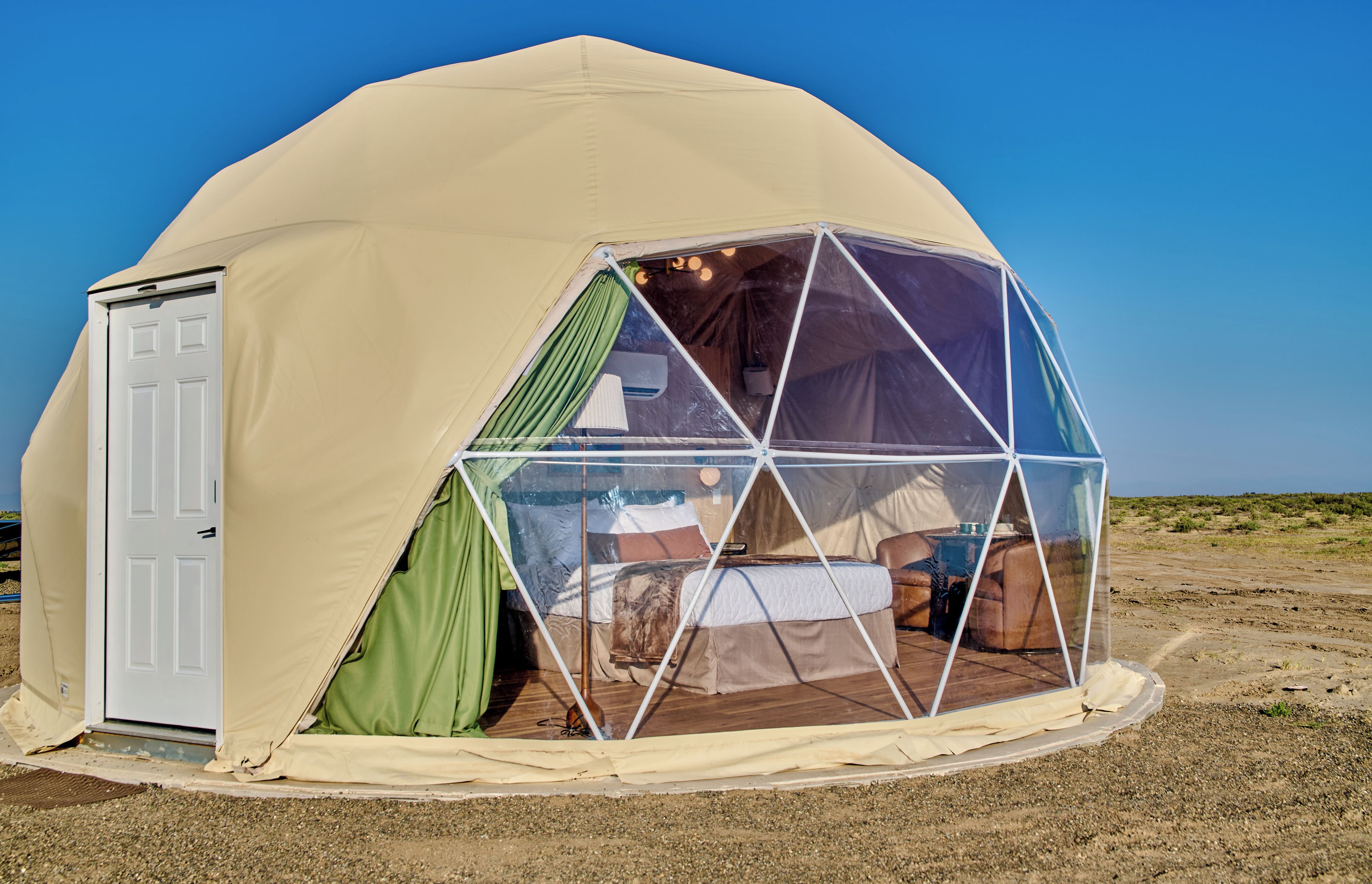 Tenda em forma de cúpula com uma porta e uma cama no interior.