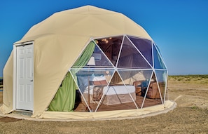 Tenda em forma de cúpula com uma porta e uma cama no interior.