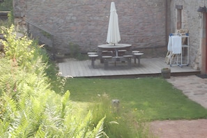 A patio area with a round table and chairs, a white umbrella, and a stone wall in the background. - Morvan Natural Park Gîte with Private Terrace, Garden, and Wi-Fi (Quarré-les-Tombes)
