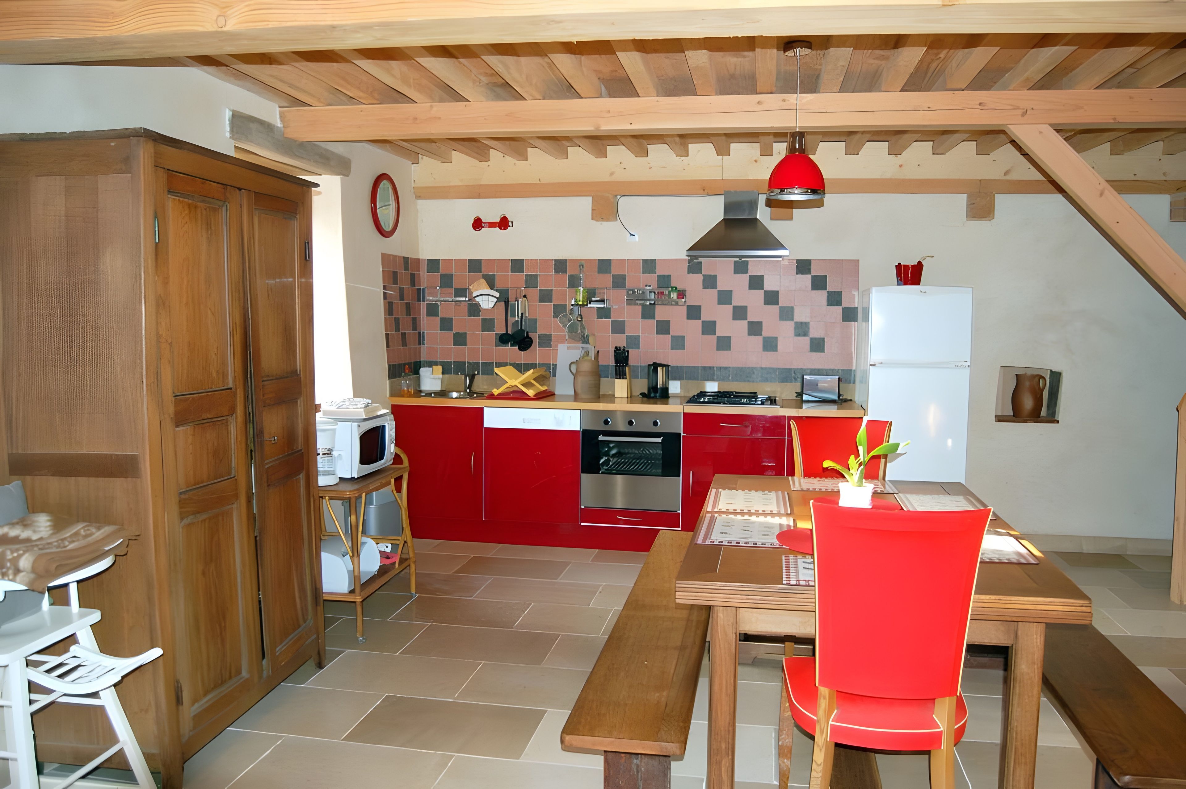 Une cuisine de taille réduite avec des meubles de rangement rouges, un four encastré et un four à micro-ondes.