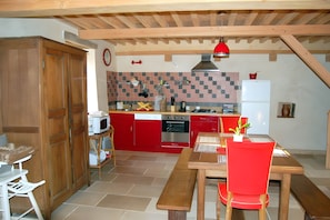 A compact kitchen with red cabinets, a built-in oven, and a microwave. - Morvan Natural Park Gîte with Private Terrace, Garden, and Wi-Fi (Quarré-les-Tombes)