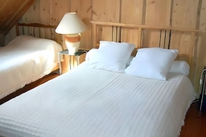 A room with a large bed, a bedside lamp, and a wooden headboard. - Morvan Natural Park Gîte with Private Terrace, Garden, and Wi-Fi (Quarré-les-Tombes)