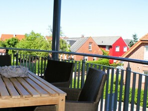 A balcony with a wooden table and two chairs, overlooking a residential area with red and grey houses. - 3 "borkum Flair" (Borkum)