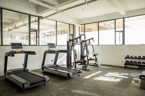A gym with treadmills, weight machines, and dumbbells. - Modern Kilimani Apt with Stunning Nairobi Views! Guest Friendly! (Nairobi)
