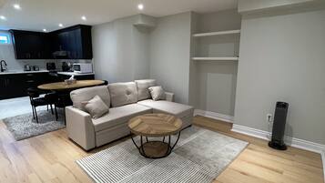 A modern living room with a sectional sofa, a round coffee table, and a kitchen in the background.