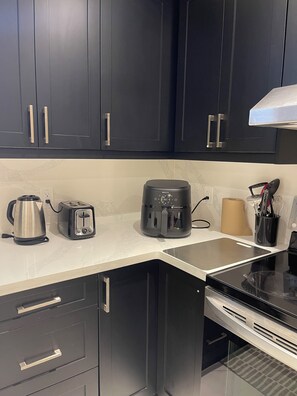 Eine moderne Küche mit dunklen Schränken, einer Kaffeemaschine, einem Wasserkocher, einem Toaster und einer Küchenpapierrolle.