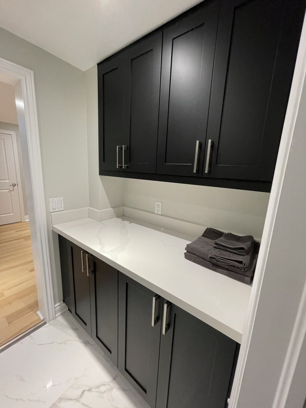 A kitchen with dark cabinets, a white countertop, and a towel rack.