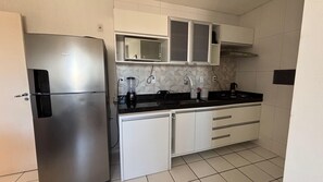 Cozinha compacta com geladeira de aço inoxidável, micro-ondas e fogão a gás.