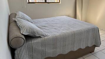 Quarto com cama, janela com vista para a cidade e piso de azulejos.