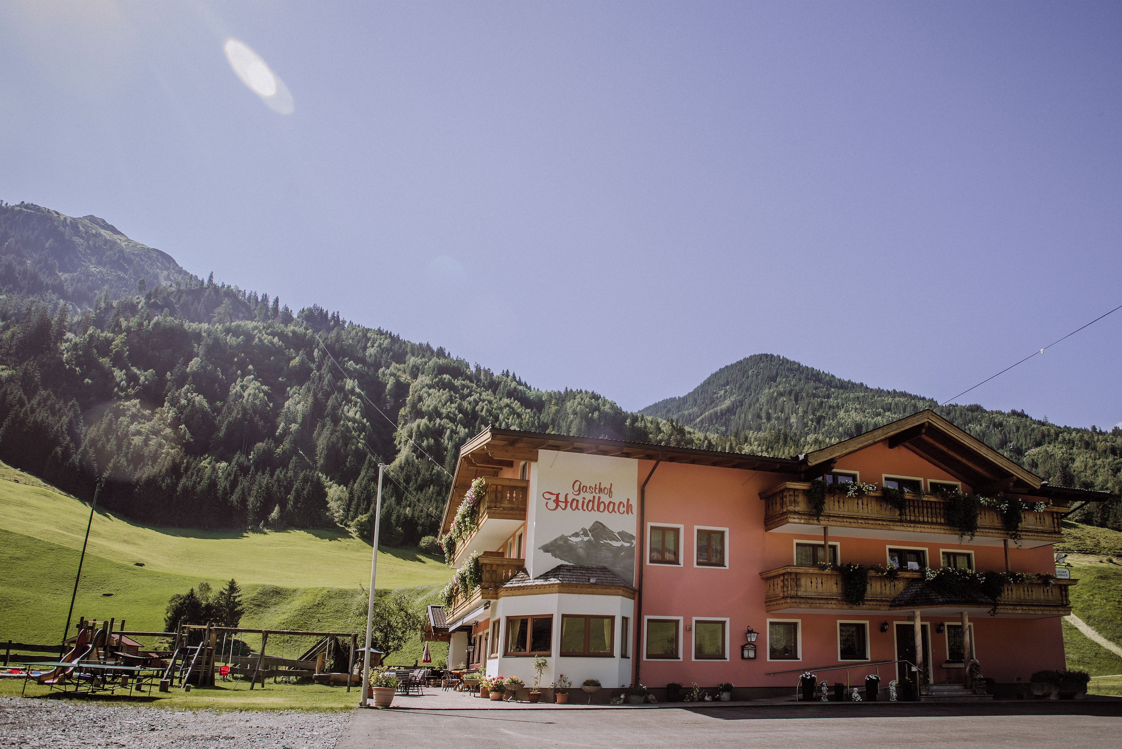 A building with a sign reading 'Gasthof Faidbach' in front of a mountainous backdrop.
