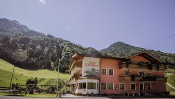 A building with a sign reading 'Gasthof Faidbach' in front of a mountainous backdrop.