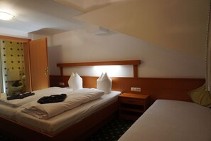 Ett hotellrum med en enkel säng, ett sängbord, ett litet bord och ett badrum som syns genom en öppen dörr.