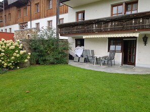 A building with a balcony, a stone wall, and a grassy yard. - Holiday Apartment With 1 Bedroom (Drachselsried)