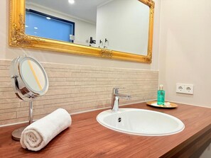 Een badkamer met een wit wastafel, een spiegel en een handdoek.
