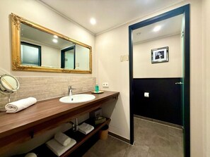 A bathroom with a wooden vanity, a large mirror, a sink, and a black door leading to the toilet. - Boutique Hotel Zuckerfabrik (Stuttgart)
