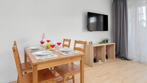 A modern dining area with a wooden table, chairs, and a flat-screen TV mounted on the wall. - Łódź | Kazimierza Odnowiciela 13 | Family Apartment | Balcony (Łódź)