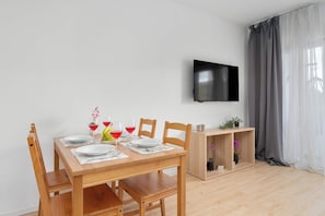 Uma sala de jantar moderna com mesa de madeira, cadeiras e televisão de tela plana na parede.