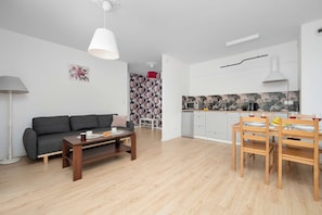 A modern living room with a sofa, coffee table, and a dining area with a table and chairs.