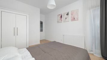 A bedroom with a bed, a wardrobe, a radiator, and a window with curtains.