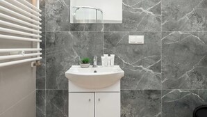 A modern bathroom with a white sink, a mirror above it, and a towel rack to the left. - Łódź | Kazimierza Odnowiciela 13 | Family Apartment | Balcony (Łódź)