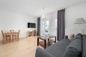 A modern living room with a grey sofa, wooden dining table, and chairs.